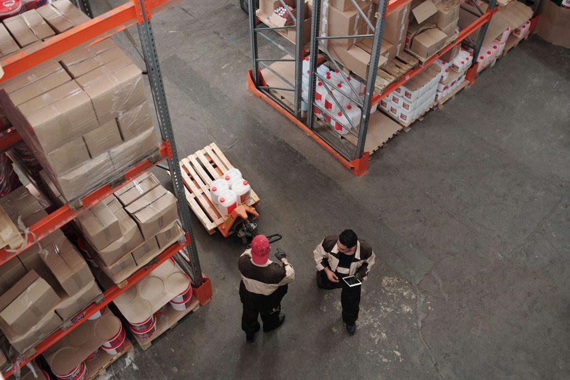 High-angle view of warehouse workers organizing inventory and pallets.
