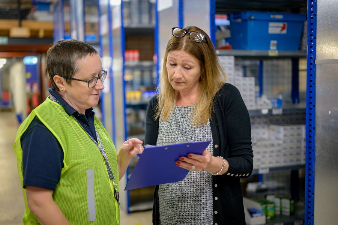 Warehouse team reviewing an inventory checklist together.