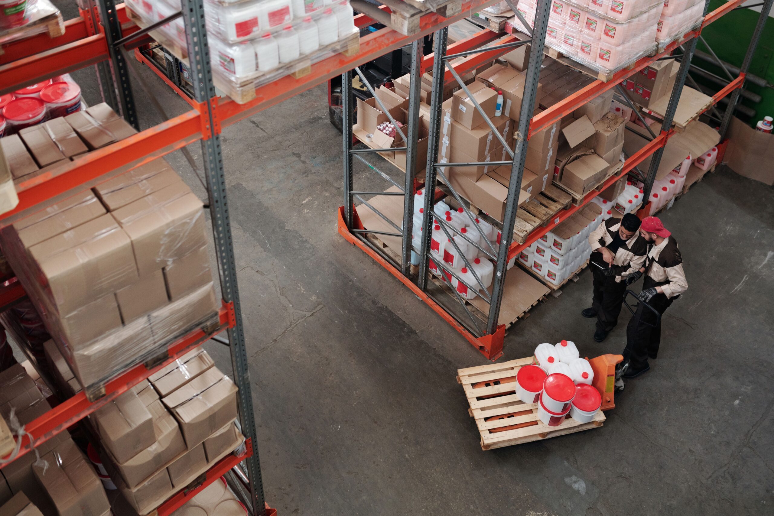 Warehouse workers discussing inventory, illustrative stock image