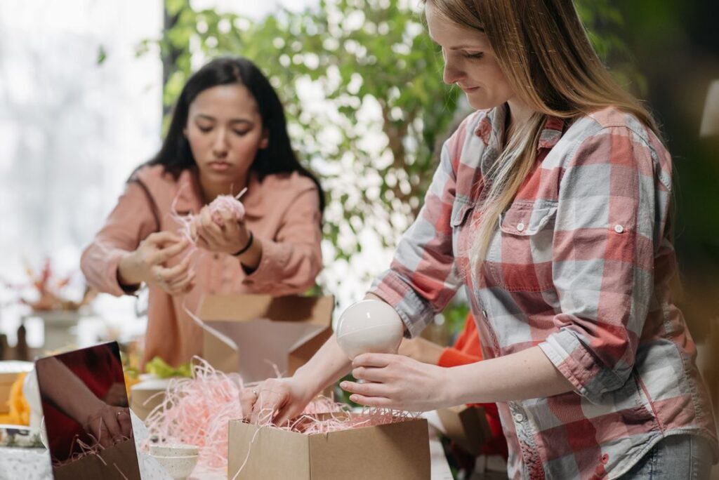 Two people packing ecommerce orders into cardboard boxes