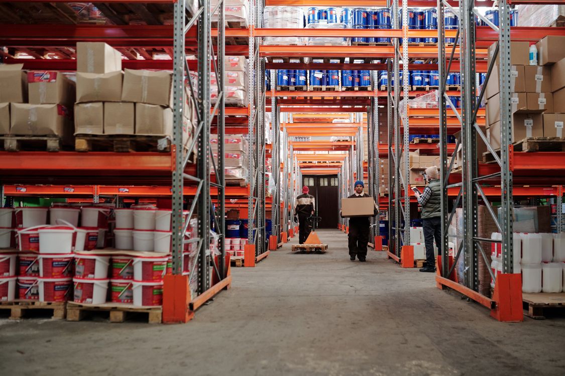 Warehouse workers handling boxes between organized storage shelves